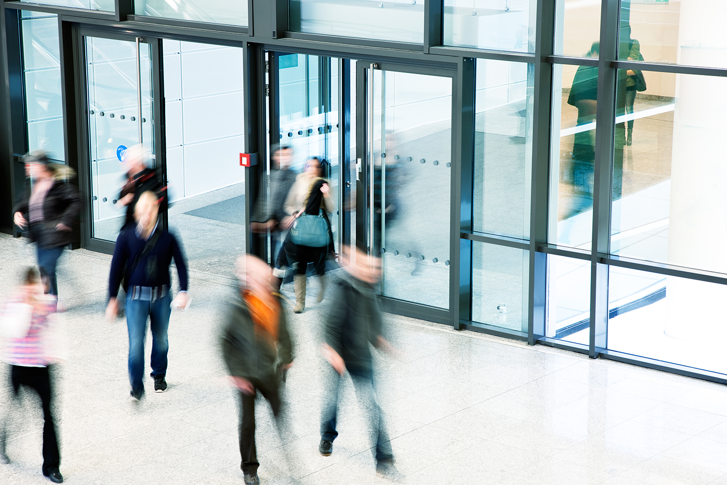 public walking around outside of a city building with glass windows