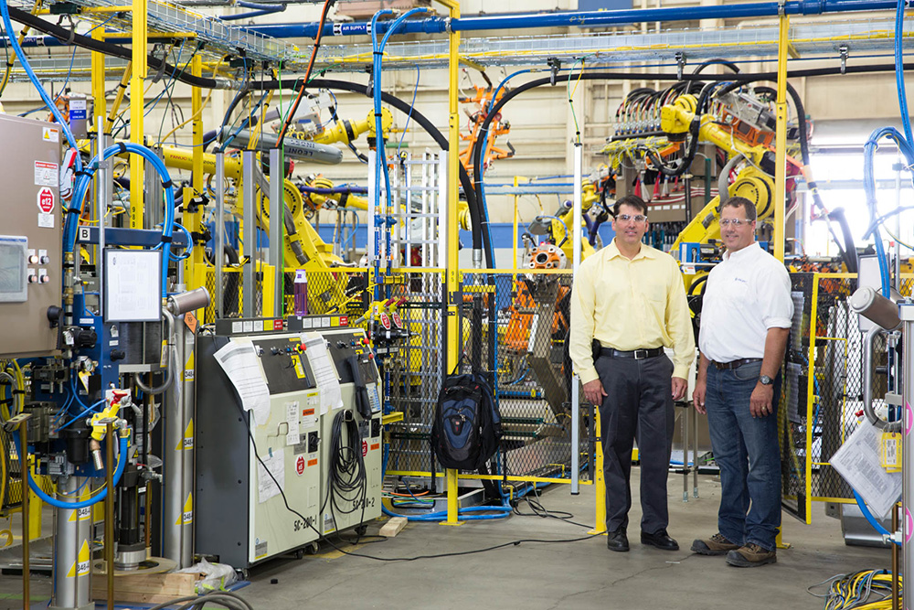 two men standing near energy-efficient technology at the Valiant TMS facility
